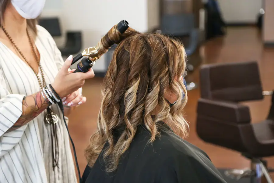 Une coiffeuse boucle les cheveux d’une cliente dans un salon.